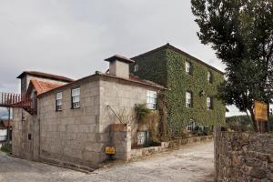 un vecchio edificio con edera sul lato. di Casa de Louredo a Paredes