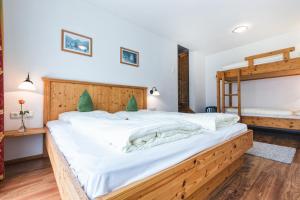 a bedroom with a large bed with white sheets at Apparthotel AlpenChalet in Neukirchen am Großvenediger