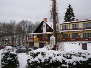 een groot gebouw met sneeuw op de grond ervoor bij Penzion u Kukačků in Horní Planá