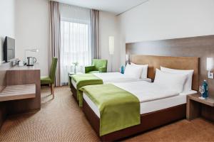 a hotel room with two beds and a desk at IntercityHotel Mainz in Mainz