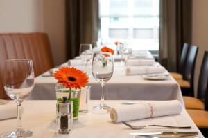 a long table with wine glasses and orange flowers on it at IntercityHotel Mainz in Mainz