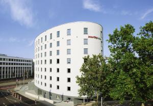 a white building with a tree in front of it at IntercityHotel Mainz in Mainz