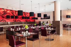 een restaurant met zwarte tafels en paarse stoelen bij IntercityHotel Mannheim in Mannheim