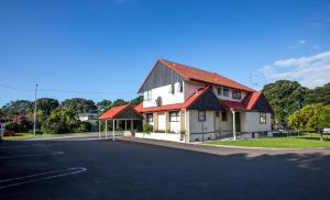 een wit huis met rode daken op een straat bij Bennetts Thermal Motor Inn in Tauranga