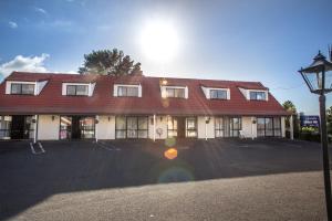 een groot rood-wit gebouw met een parkeerplaats bij Bennetts Thermal Motor Inn in Tauranga