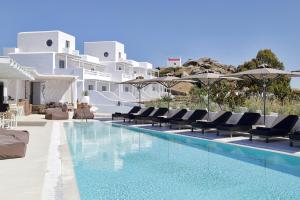 a pool with chairs and umbrellas next to a resort at Livin Mykonos Hotel - Adults Only in Mýkonos City