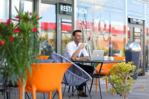 een man aan een tafel met een laptop bij Hotel Porto in Radomsko