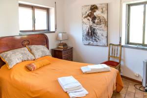 een slaapkamer met een oranje bed met 2 handdoeken erop bij Moby Dick Lodge in Malveira da Serra