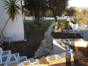 a garden with white chairs and a tree and a sidewalk at Archipelagos in Naxos Chora