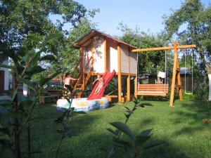 een klein huis met een speeltuin in de tuin bij Pokoje i domki nad Kanałem Bystrym in Augustów