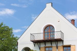 uma casa branca com um telhado de gambrel e uma varanda em Figula Vendégház em Balatonfüred