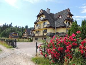 a large house with a black roof and red flowers at Apartamenty Bajka Białka Tatrzanska z Kuchnią tel 60806 - 4835 in Białka Tatrzanska