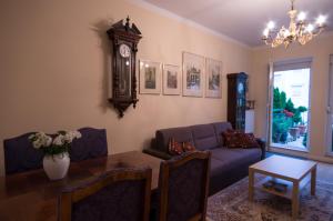 a living room with a couch and a table and a clock at Apartament Mundus in Sopot