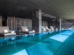 a large swimming pool with a row of white chairs at Algarve Race Resort - Hotel in Montes de Cima