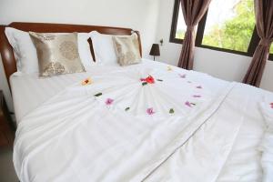 Una cama blanca con flores encima. en Lone Self-Catering Apartment, en Baie Sainte Anne