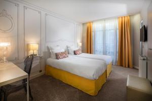 een hotelkamer met een groot bed en een bureau bij Hôtel Paris Vaugirard in Parijs