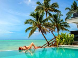 een vrouw in een zwembad naast de oceaan bij Crystal Blue Lagoon Villas in Rarotonga