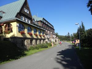 un bâtiment avec des boîtes de fleurs sur les fenêtres d'une route dans l'établissement Hotel Tanecnica, à Pustevny