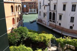 um canal com um barco na água entre edifícios em Pensione Accademia - Villa Maravege em Veneza