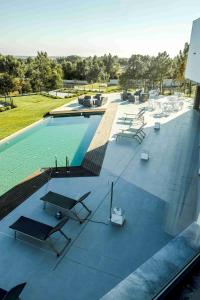 una piscina con tavoli e sedie in un edificio di Enigma - Nature & Water Hotel a São Teotónio