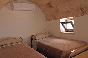 two beds in a small room with a window at Dimora Dioniso in Polignano a Mare