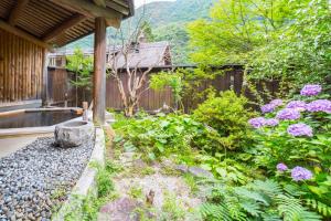 um jardim com flores roxas e uma cerca em Kazeya em Takayama