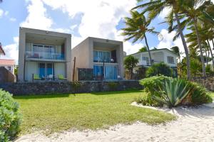 uma casa na praia com palmeiras em Turquoise Bay Beach Apartments Trou d'Eau Douce em Trou dʼ Eau Douce