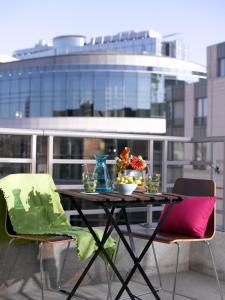 een tafel en stoelen met een kom bloemen op een balkon bij Thon Hotel Residence Parnasse Aparthotel in Brussel