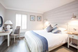 a white bedroom with a bed and a desk and a chair at Master Builder's House Hotel in Beaulieu