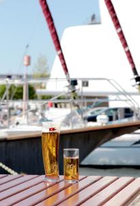 dois copos de cerveja sentados numa mesa de madeira com um barco em Pension Klabautermann em Stralsund