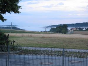 einen Zaun vor einem Feld mit Nebelfeld in der Unterkunft Ferienwohnung Am Kapellenäcker in Neumarkt in der Oberpfalz