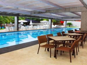 - un billard avec des tables et des chaises à côté de la piscine dans l'établissement Apartamento Suites Le Jardin Caldas Novas Goiás, à Caldas Novas