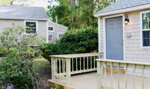 a wooden porch with a blue door on a house at Sandwich Inn and Suites in Sandwich