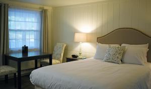 a bedroom with a bed and a desk and a window at Sandwich Inn and Suites in Sandwich