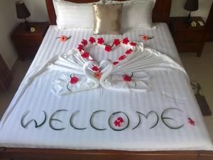 Una cama blanca con un cartel de bienvenida. en Lone Self-Catering Apartment, en Baie Sainte Anne