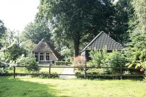 ein Haus mit einem Zaun vor einem Hof in der Unterkunft Gastenverblijf Het Muzehuis in Dalfsen