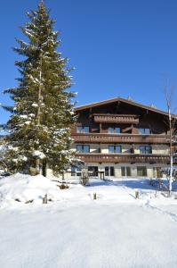 un grand bâtiment avec un pin dans la neige dans l'établissement Hotel Wieser, à Mittersill