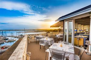 ein Restaurant mit Tischen und Stühlen auf einem Balkon in der Unterkunft Grand Hotel Ortigia in Syrakus