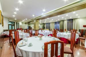 een eetkamer met witte tafels en stoelen bij Galicia Palace in Pontevedra