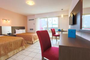 a hotel room with two beds and a red chair at Crown Paradise Club All Inclusive in Puerto Vallarta