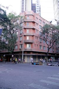 een roze gebouw waar mensen voor lopen bij Estoril Hotel in Belo Horizonte