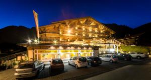 un edificio con coches aparcados delante de él por la noche en Hotel Alphof Alpbach, en Alpbach