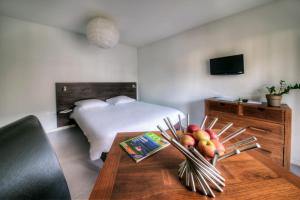 - une chambre avec un lit et une table avec des fruits dans l'établissement Zenitude Hôtel-Résidences l'Acacia Lourdes, à Lourdes