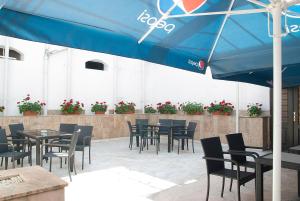 a patio with tables and chairs and a blue umbrella at Hotel Dacia in Lugoj