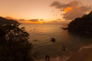 un gruppo di persone in acqua al tramonto di SeaScape on Heavenly Bay a Castara