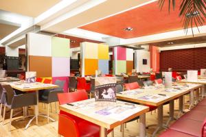 un restaurante con mesas de madera y sillas coloridas en Hotel Tristar, en La Louvière