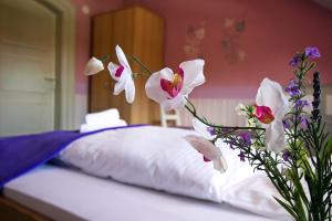 a vase filled with flowers next to a bed at Hotel Neun 3/4 in Celle