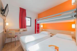 ein Hotelzimmer mit 2 Betten und einem Schreibtisch in der Unterkunft Première Classe La Rochelle Centre - Les Minimes in La Rochelle