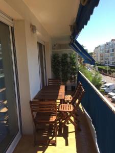 einen Balkon mit einem Holztisch und Stühlen in der Unterkunft Immeuble le St Honorat in Cannes