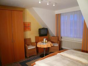 Schlafzimmer mit einem Bett, einem Tisch und einem TV in der Unterkunft Hotel-Restaurant Nord-Stuv in Cuxhaven